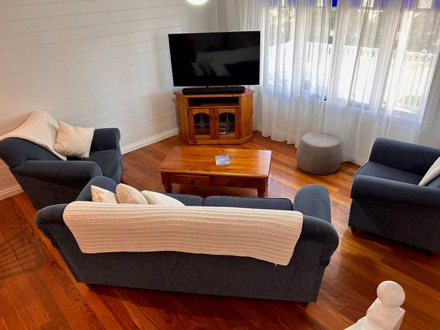 Sails villa lounge with navy sofas, timber floors and TV