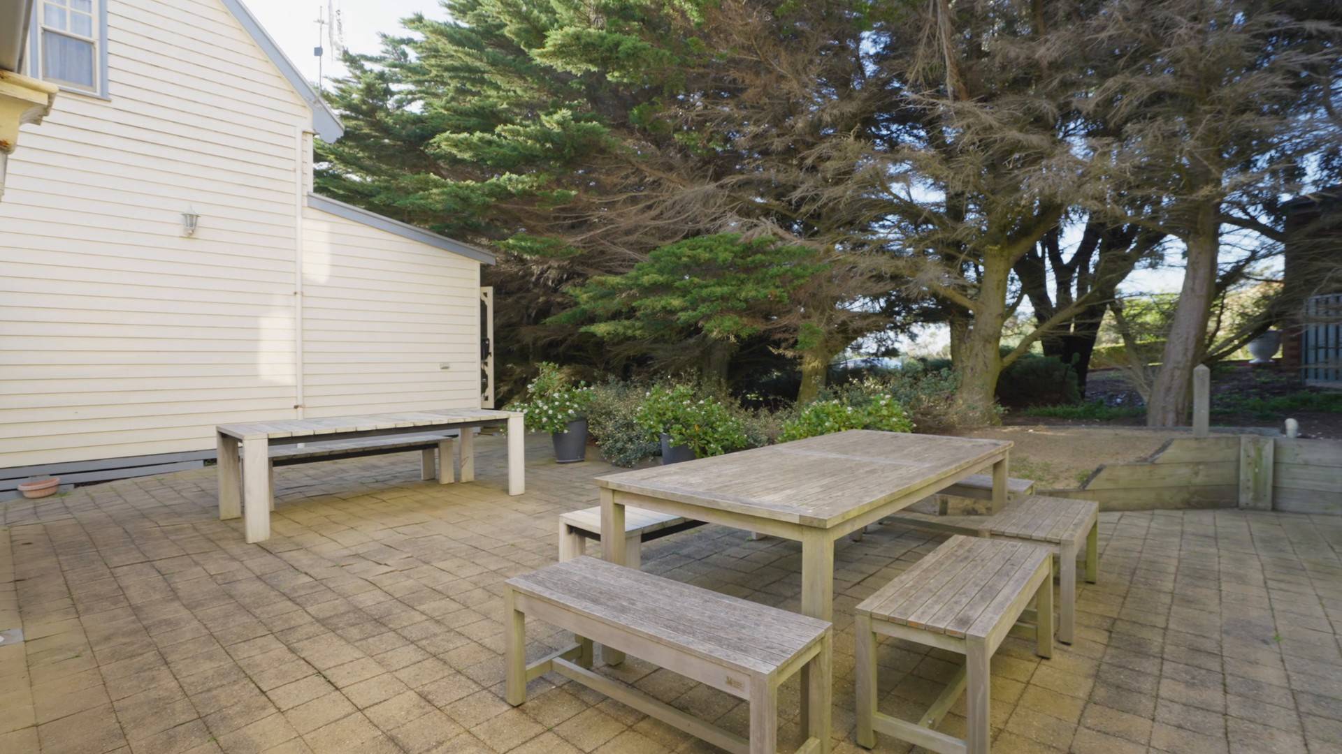 Timber deck with outdoor table and bench seating beside the Dunes villa