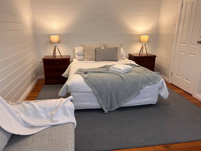 Sails villa queen bedroom with grey throw and bedside lamps
