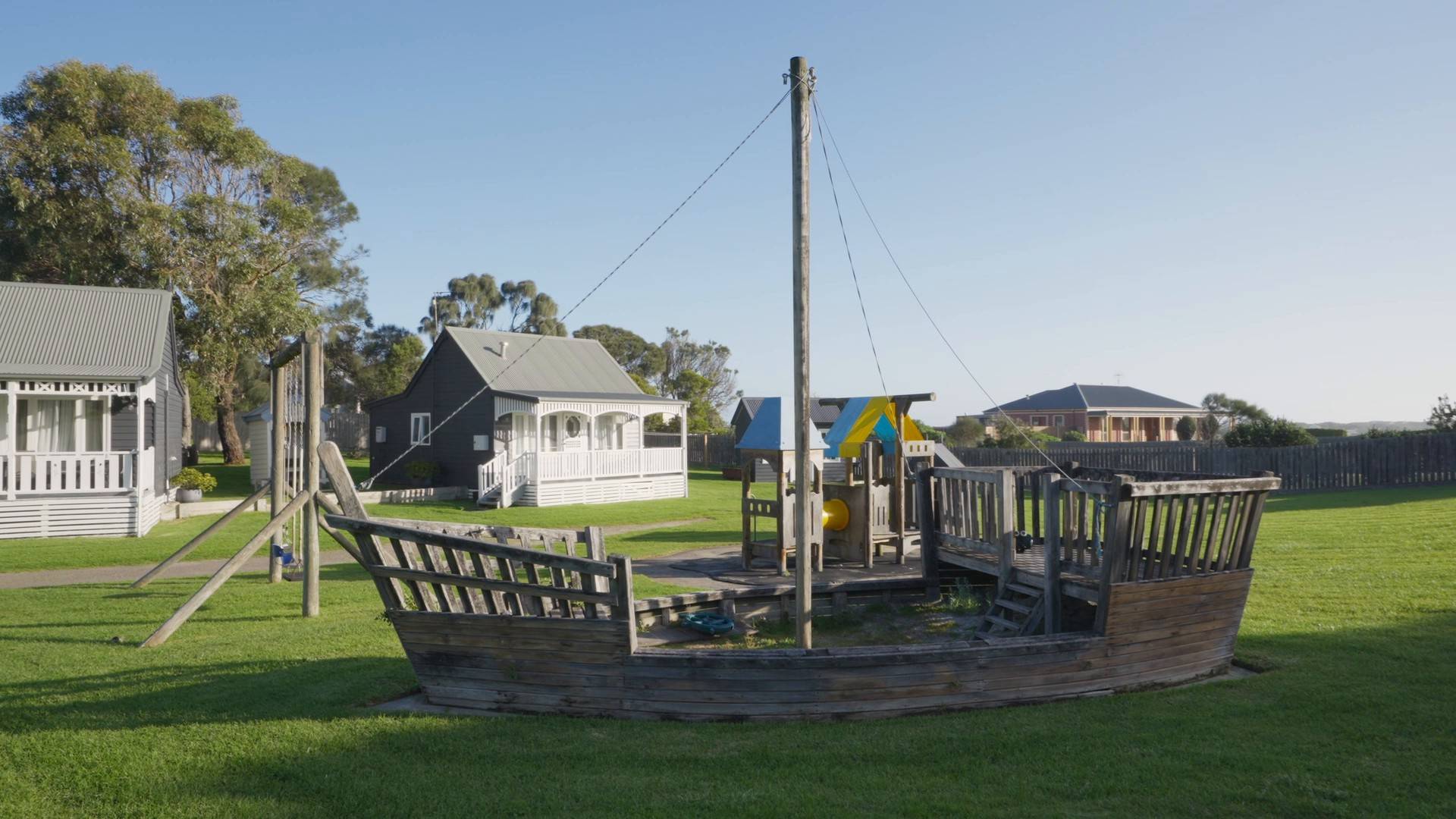 Children's pirate-ship play structure on the lawn, with villas in the background
