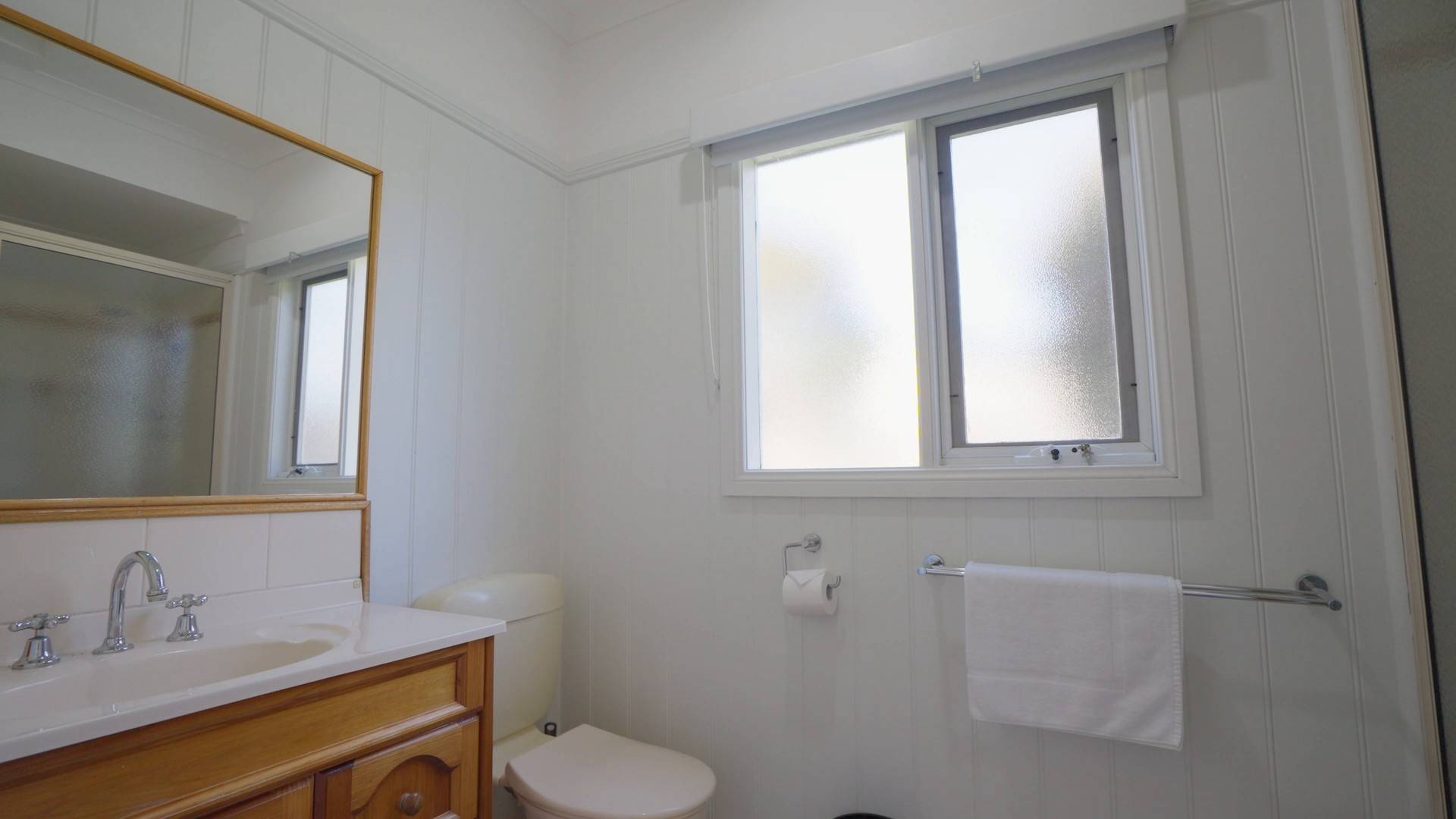 Clean white villa bathroom with vanity, mirror and frosted window